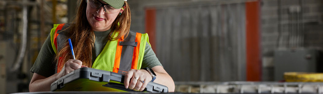 Woman in neon yellow safety vest working on tablet