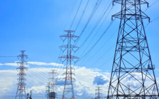 Image of several transmission lines with a cloudy but blue sky in the background